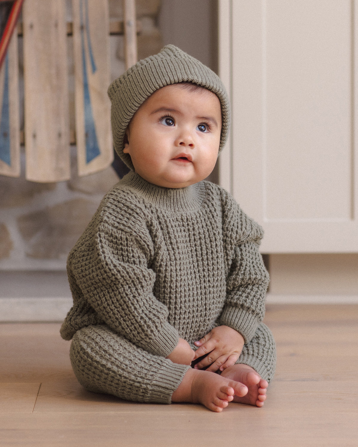Styled Infant model wearing Quincy Mae Baby Luca Pant in Spruce, Quincy Mae Chunky Knit Baby Sweater in Spruce, and Quincy Mae Beanie in Spruce