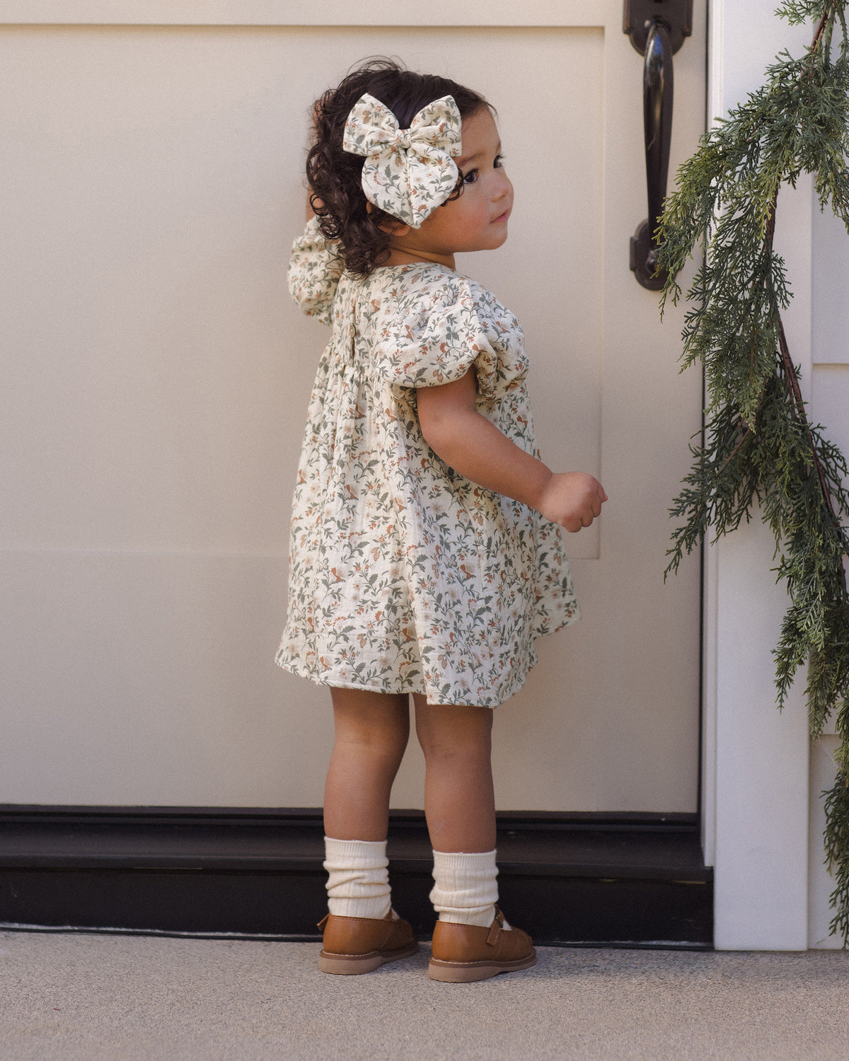Quincy Mae Carina Baby Dress in Holiday Floral full length lifestyle back to camera photo
