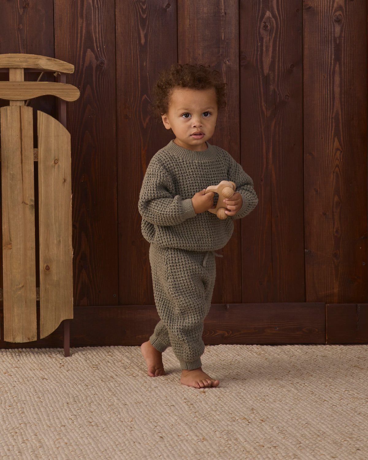 Baby model wearing Quincy Mae Chunky Knit Baby Sweater in Spruce and Quincy Mae Baby Luca Pant in Spruce