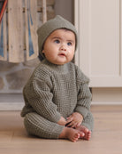 Styled Infant model wearing Quincy Mae Baby Luca Pant in Spruce, Quincy Mae Chunky Knit Baby Sweater in Spruce, and Quincy Mae Beanie in Spruce