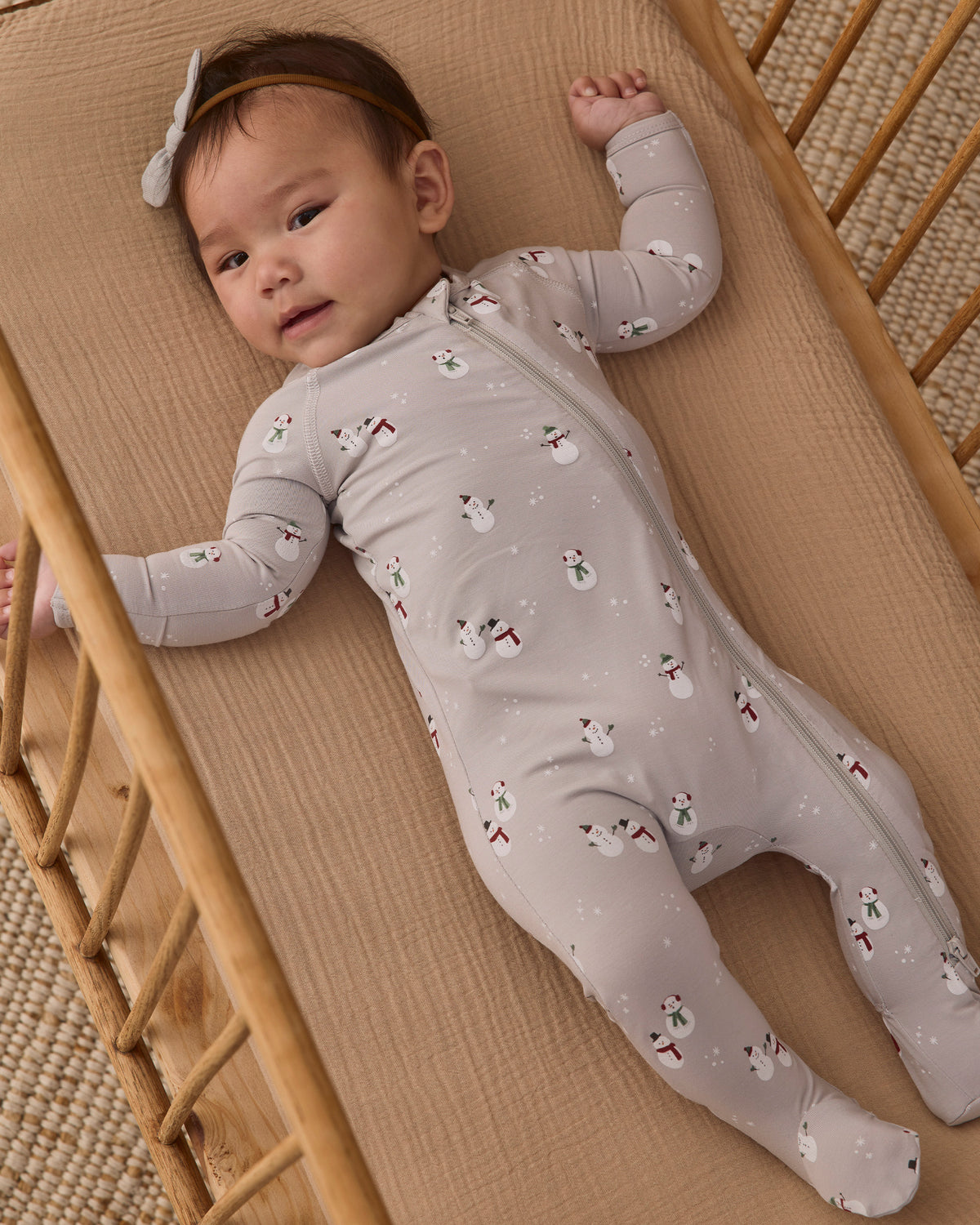 Baby girl model wearing Quincy Mae Baby Bamboo Zip Footie in Snowman 