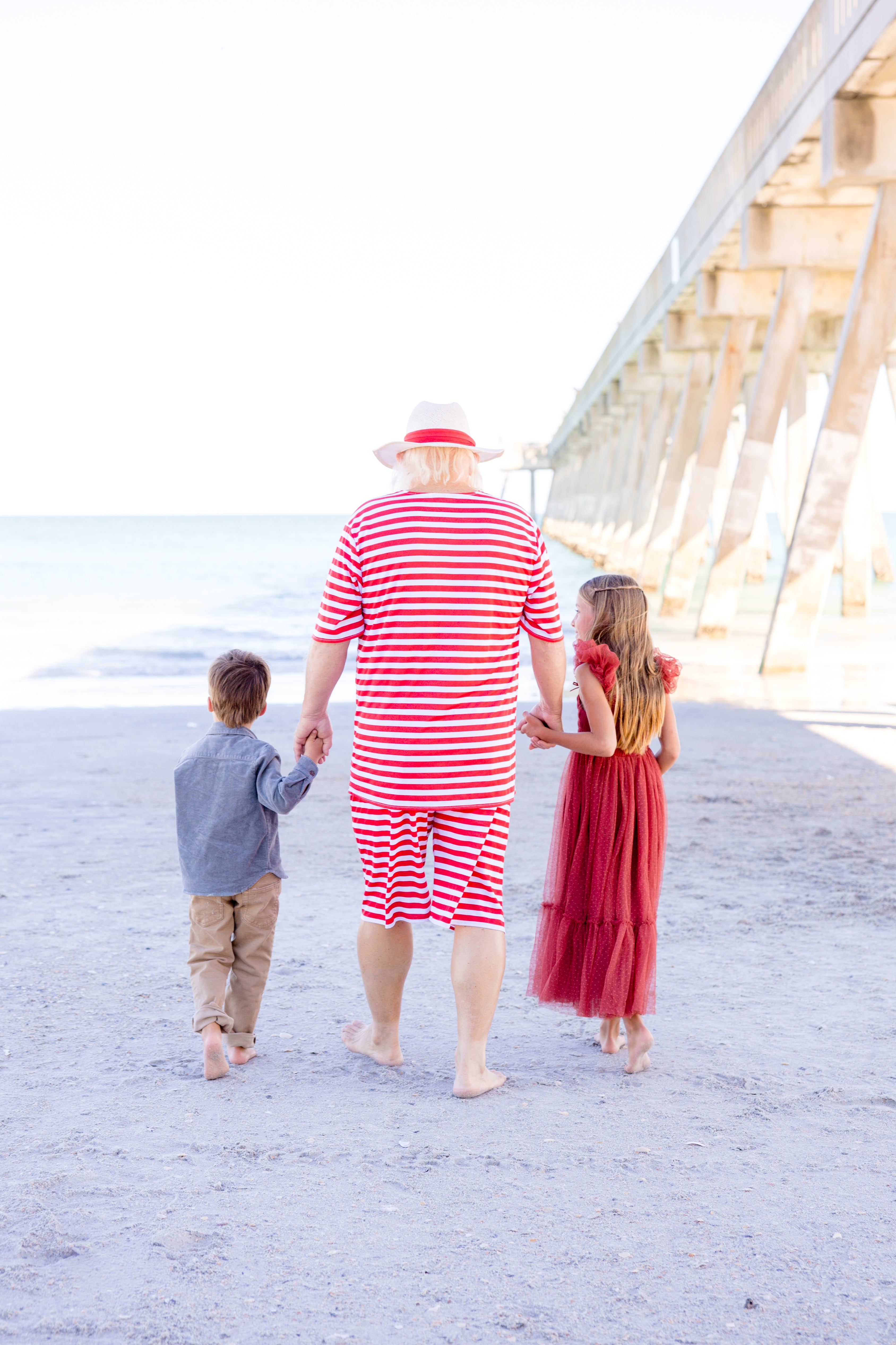 ruby red dress facing the ocean holding Santa's hand 