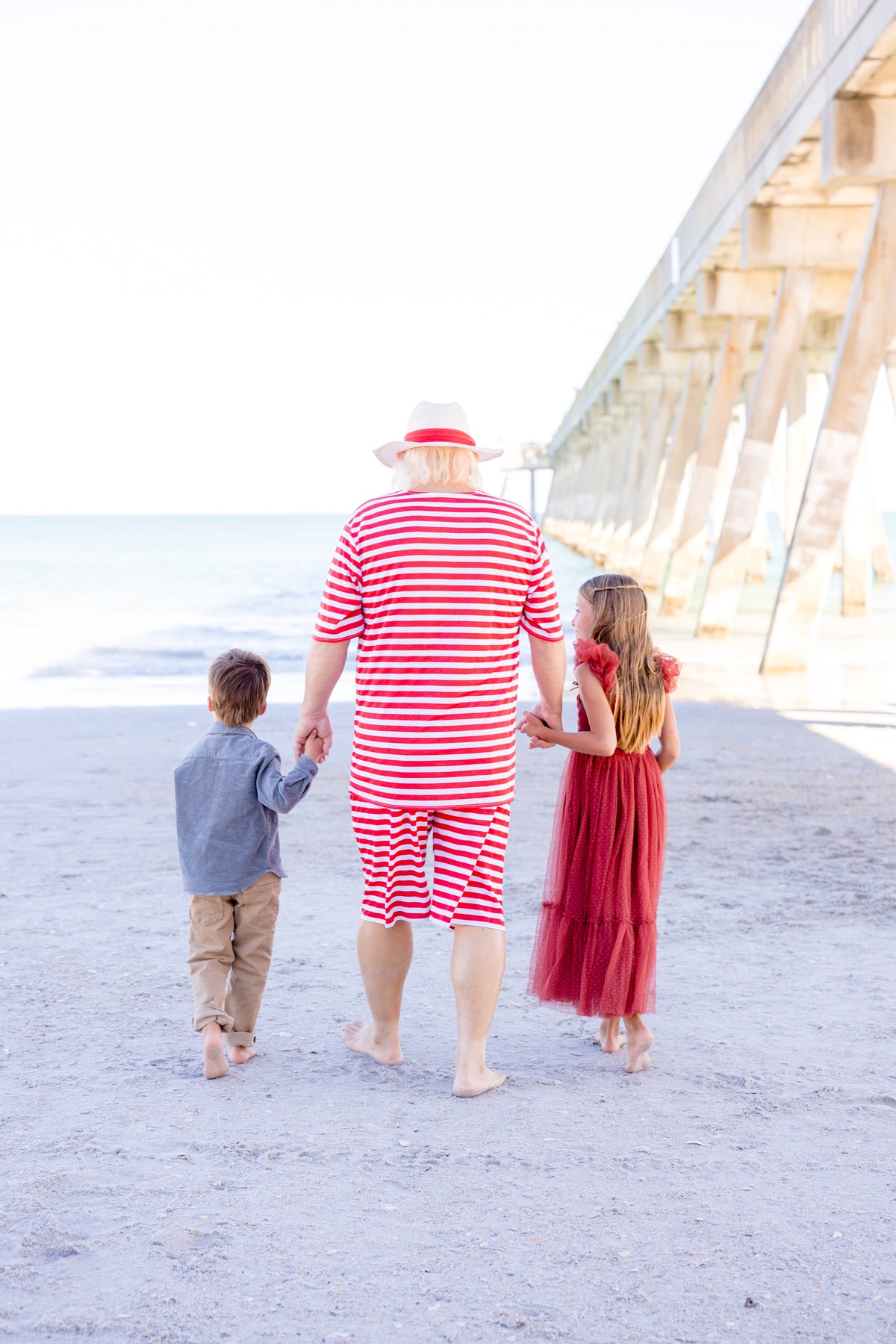 ruby red dress facing the ocean holding Santa's hand 